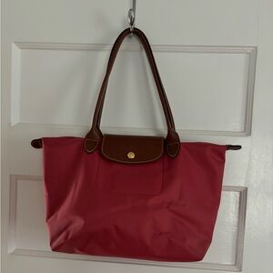 Longchamp Le Pliage original M tote bag in raspberry red with leather handles.